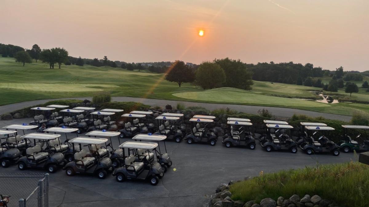 Two rows of Golf carts at a golf course at dawn.